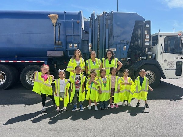 Students and teachers pose in front of a Solid Waste truck at a Trash in the Class field trip.