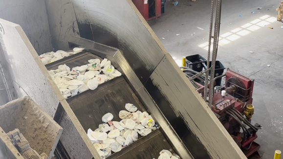 Conveyor belt prepares separated recycling for bailing.