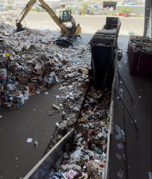 Recyclable material enters the sorting process on a conveyor belt.