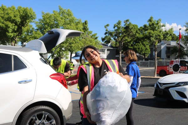 Volunteers carrying donated clothes from a car at the Recyclothes clothing drive.