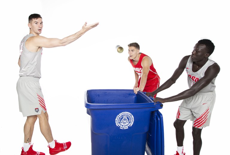 UNM Lobo Basketball Players throwing cans in a recycle bin.