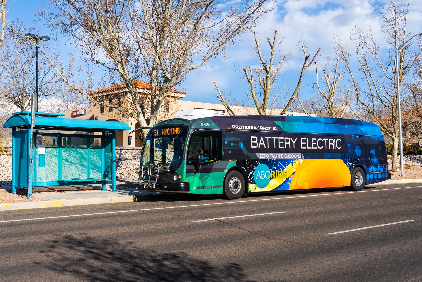 An electric ABQ RIDE bus stopped at a bus stop.
