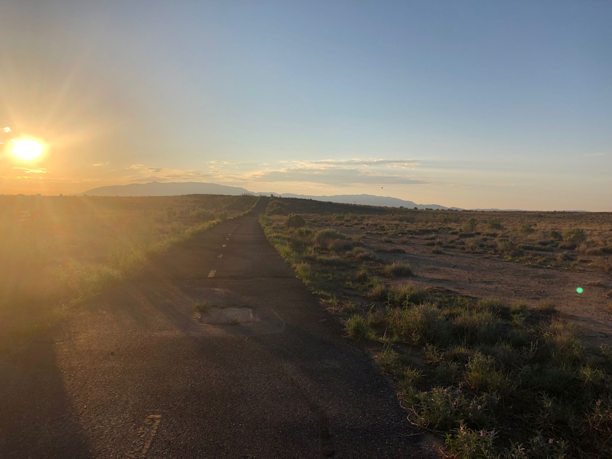 An image of the sun low in the morning sky and the empty road stretching out ahead.