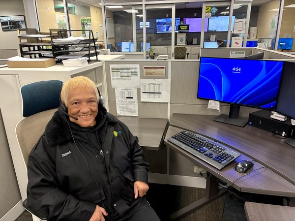 Customer Service Customer service agent with headset, seated at desk with computer smiling as she answers phone calls.