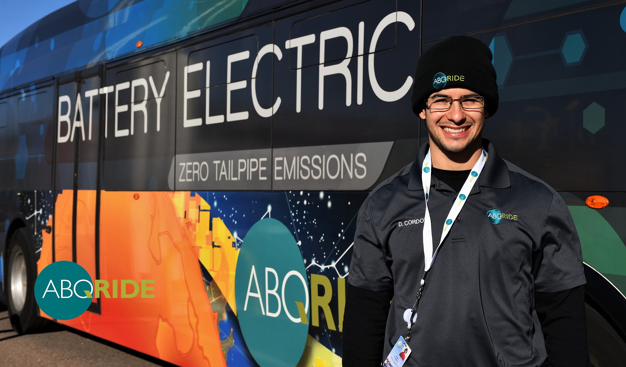 An ABQ RIDE employee standing in front of a bus.