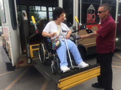 Image of a Sun Van driver assisting a passenger in a wheelchair board a Sun Van. 